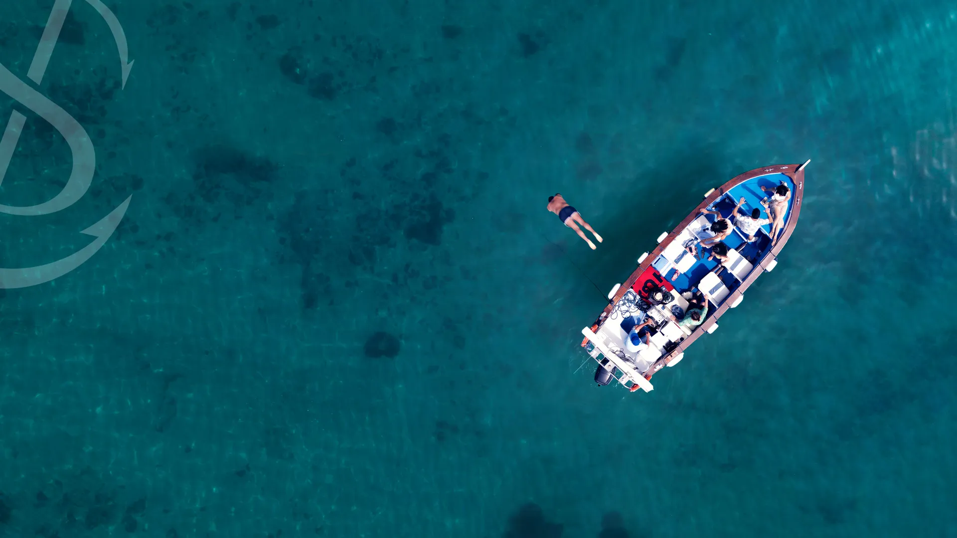 aerial photo of people on a boat while one is diving